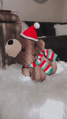 a brown teddy bear wearing a santa hat and scarf on top of a white fur rug