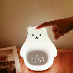 a white bear shaped alarm clock sitting on top of a wooden table