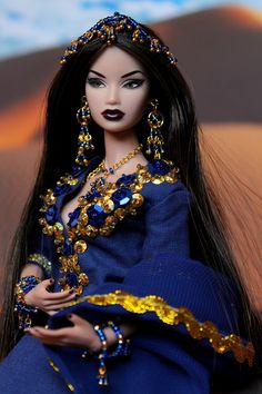 a doll with long black hair wearing a blue dress and gold jewelry on it's head