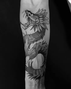 a black and white photo of a dragon tattoo on the right arm, with its tail curled up