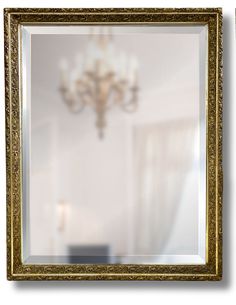 a gold framed mirror with a chandelier hanging from it's side in front of a white wall