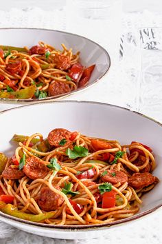 two white bowls filled with spaghetti and vegetables