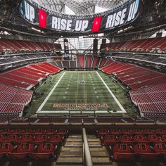 an empty football stadium with red seats and a big sign above the field that says rise up rise up