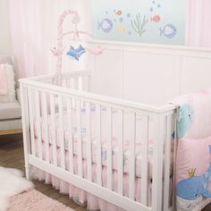 a white crib with pink and blue bedding in a baby's room