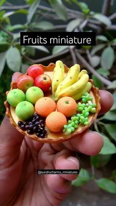 a hand holding a small bowl filled with fruits and vegetables on it's side