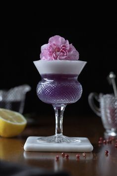 a glass vase filled with pink flowers on top of a table next to lemons