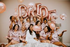 a group of women sitting on top of a bed in front of balloons and letters