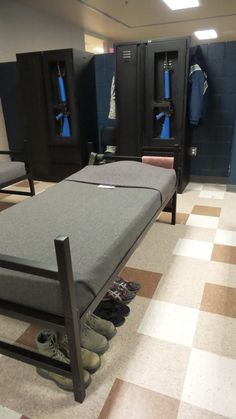 a row of lockers with shoes on the floor in front of them and one bench at the end