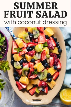 a bowl filled with fruit salad next to lemons, strawberries and blueberries