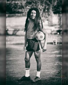 a black and white photo of a man with dreadlocks holding a soccer ball