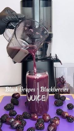 a person pouring juice into a glass next to blackberries