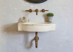 a white sink sitting under a black clock mounted on a wall next to a potted plant