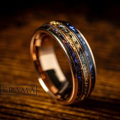 a gold ring with multicolored stones in it on top of a wooden table