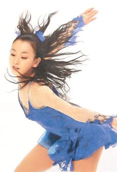 a woman in blue is dancing with her hair flying through the air and she has long black hair