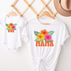 two baby onesuits with flowers and the word mama on them hanging from a clothes rack