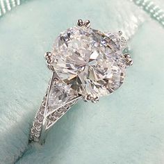 an oval cut diamond ring sitting on top of a cushion