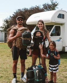 a man, woman and two children standing in front of a camper