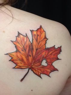 a woman's shoulder with a tattoo design of a maple leaf on the back