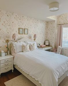 a white bed sitting in a bedroom next to a wallpaper covered with pink flowers