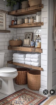 a white toilet sitting next to a wooden shelf filled with towels