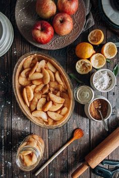 apples, oranges and other ingredients are arranged on a wooden table with utensils