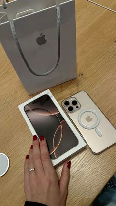 a woman's hand is touching an apple phone next to her bag and other accessories