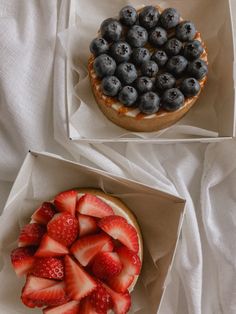 two pies with strawberries and blueberries on top