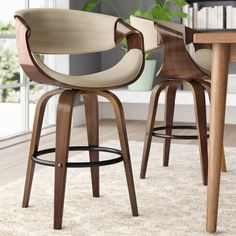 two wooden stools in front of a table and bookshelf with plants on it