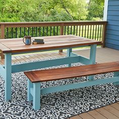 a wooden table and bench on a deck with blue walls, black and white patterned rug