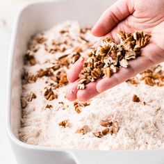 a person scooping granola into a white dish