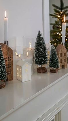 small christmas trees on a mantle with lit candles in front of the house and tree