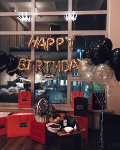 a birthday party with balloons and gifts in front of a window that says happy birthday