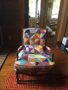 a colorful patchwork chair sitting on top of a red rug