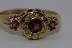 Antique 18ct Garnet & Diamond ring has been restored to enhance its beauty. The ring contains 1 4.50mm bezel set Rhodolite Garnet surrounded by 10 1.25mm diamonds & 2 3 mm claw set shoulder garnets mounted onto a 4.00 -2.20mm wide tapered band Hallmarked Crown, 18 Anchor, V  Total Weight 3.18 grams Rhodolite Jewelry, Medieval Ring, Antique Rings Victorian, Medieval Rings, Garnet And Diamond Ring, Medieval Jewelry, Ancient Jewelry, Fancy Jewellery, Rhodolite Garnet