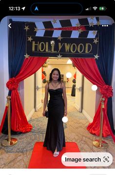 a woman standing in front of a hollywood sign at the entrance to a movie theater