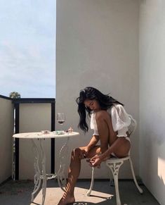 a woman sitting at a table with a glass of wine in front of her on the balcony