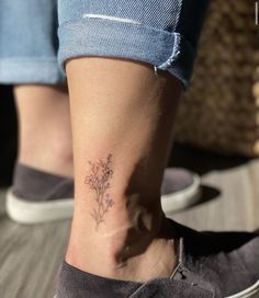 a woman's foot with a small flower tattoo on her left ankle and the bottom part of her leg