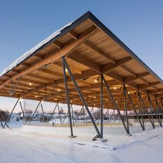 an outdoor covered structure in the snow with lights shining on it's roof and metal poles sticking out from underneath