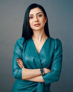 a woman with her arms crossed and wearing a green dress, posing for a photo