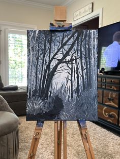 an easel with a painting on it in the middle of a living room area