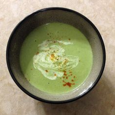 a bowl filled with green soup on top of a table