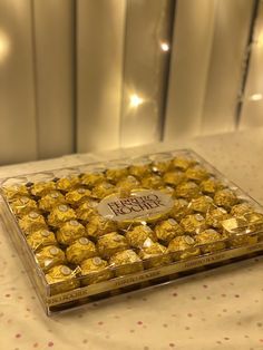 a clear box filled with chocolates on top of a white tablecloth covered table