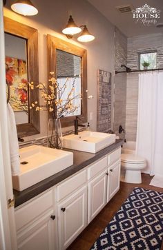 a bathroom with double sinks and two mirrors on the wall next to a shower curtain