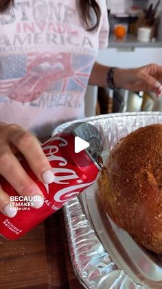 a woman is pouring soda into a loaf of bread on a plate with another person in the background