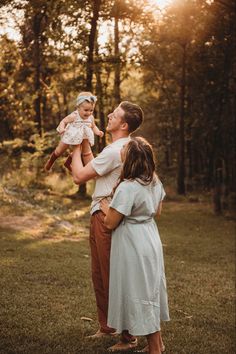 a man holding a baby up in the air while standing next to two other people