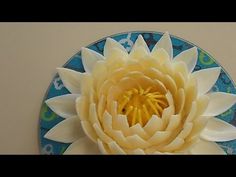 a white flower sitting in the center of a blue and white circular wall hanging ornament