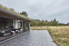 an outdoor living area with grass on the roof and couches in the foreground