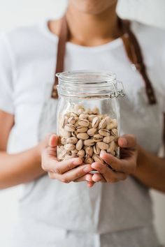 a woman holding a jar filled with nuts