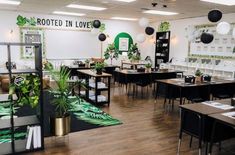 a room with tables, chairs and plants on the wall in front of it that says rooted in love