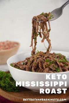 a bowl filled with shredded meat and garnished with parsley on the side